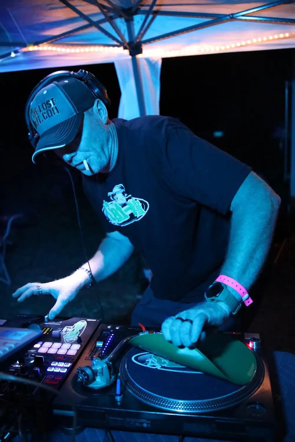 DJ Natural Nate® under blue tent lighting scratching on green slipmat, The-Lost-Art.com hat